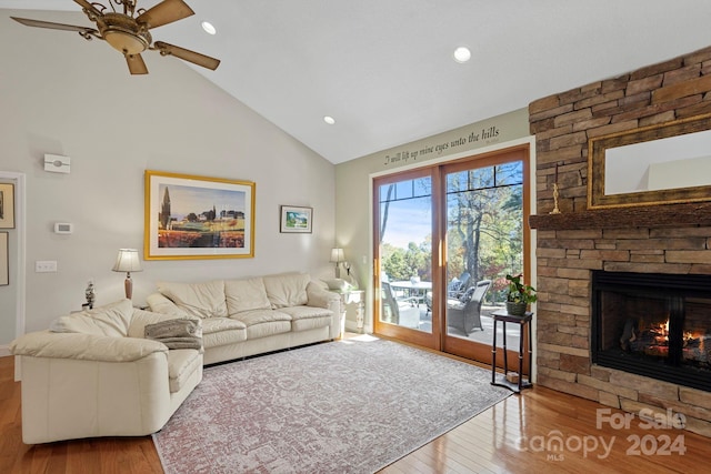 living room with a stone fireplace, hardwood / wood-style flooring, high vaulted ceiling, and ceiling fan