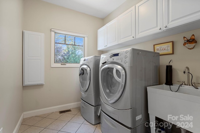 laundry room with sink, light tile patterned flooring, washing machine and dryer, and cabinets