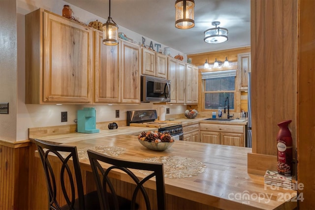 kitchen with butcher block countertops, stainless steel appliances, light brown cabinetry, and sink