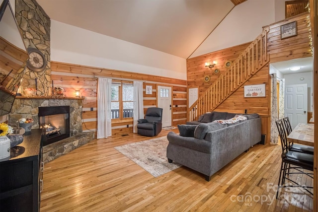 living room featuring hardwood / wood-style floors, high vaulted ceiling, a fireplace, and wooden walls