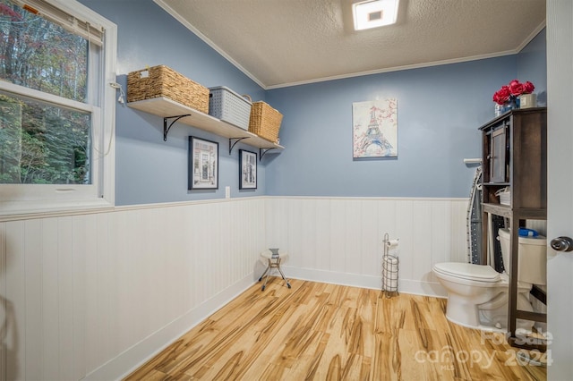 clothes washing area with ornamental molding, a textured ceiling, and wood-type flooring