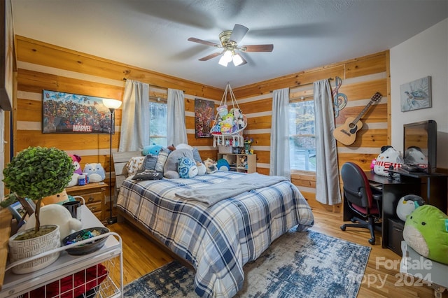 bedroom with wood walls, hardwood / wood-style flooring, and ceiling fan