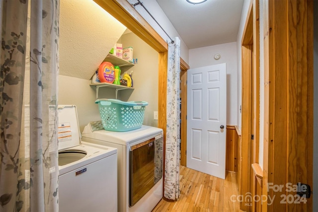 clothes washing area with independent washer and dryer, a textured ceiling, and light wood-type flooring