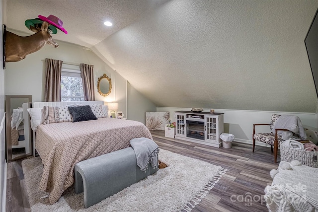 bedroom featuring hardwood / wood-style flooring, a textured ceiling, and lofted ceiling