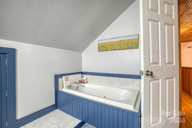 bathroom with hardwood / wood-style floors, a textured ceiling, vaulted ceiling, wood walls, and a washtub