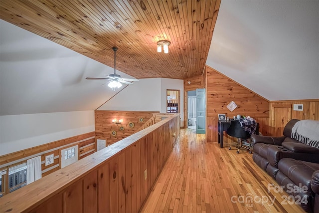 interior space with light hardwood / wood-style flooring, wooden walls, wood ceiling, and vaulted ceiling