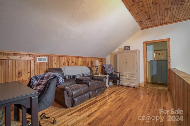 interior space with wooden walls, light wood-type flooring, and vaulted ceiling