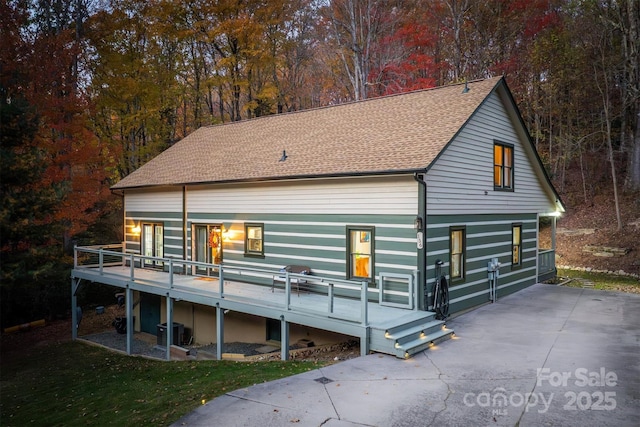 view of front of house with central AC, a wooden deck, and roof with shingles