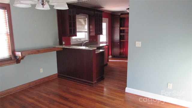 kitchen featuring a notable chandelier, sink, kitchen peninsula, and dark hardwood / wood-style floors