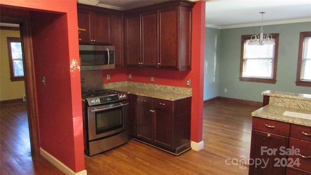 kitchen with stainless steel appliances, light stone countertops, ornamental molding, and light wood-type flooring