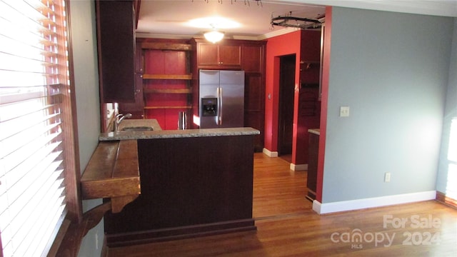 kitchen with hardwood / wood-style flooring, kitchen peninsula, ornamental molding, stainless steel fridge, and sink