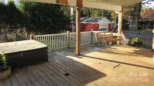 wooden deck featuring a hot tub and a storage unit