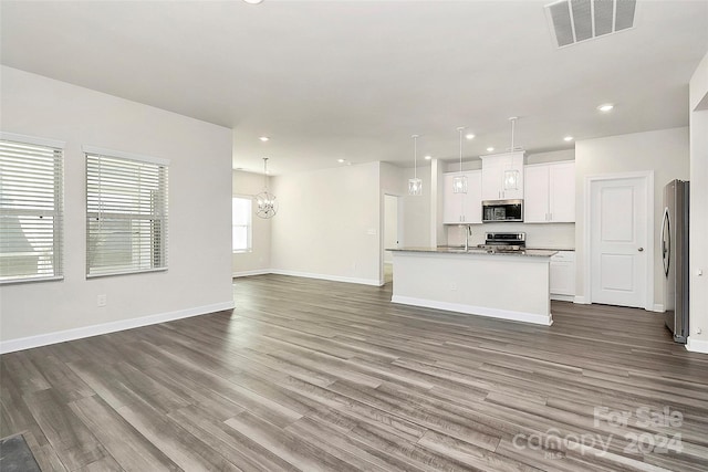 unfurnished living room with dark wood-type flooring, sink, and a chandelier