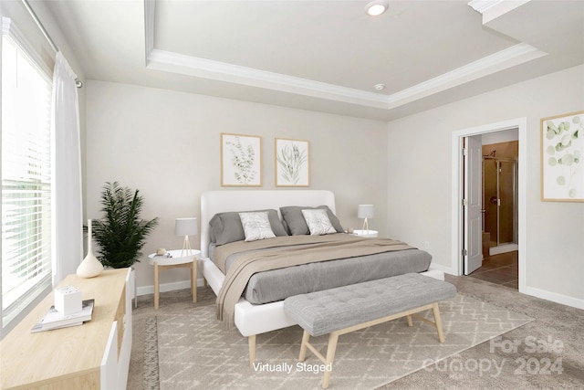 bedroom with crown molding, carpet floors, ensuite bathroom, and a tray ceiling