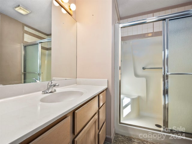 bathroom with vanity, walk in shower, and a textured ceiling