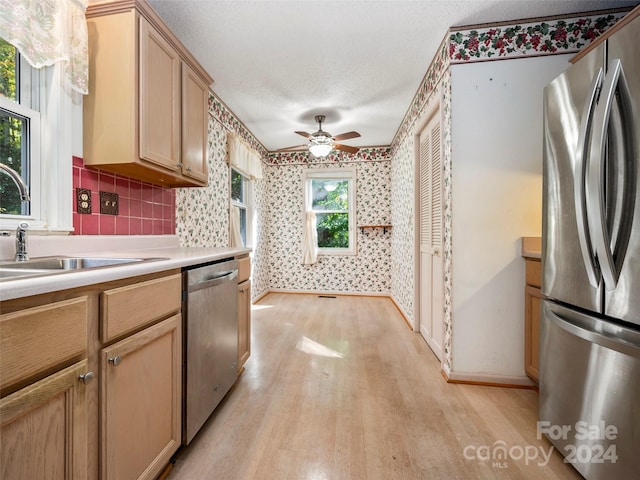 kitchen featuring ceiling fan, stainless steel appliances, a textured ceiling, and light hardwood / wood-style flooring