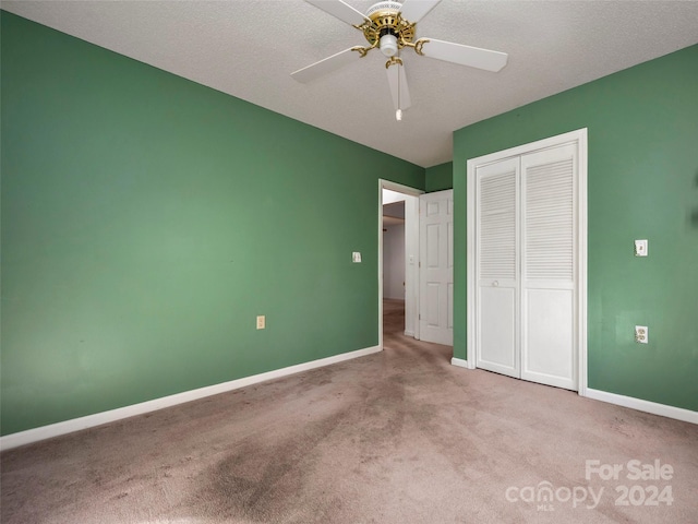 unfurnished bedroom featuring a closet, ceiling fan, a textured ceiling, and light colored carpet