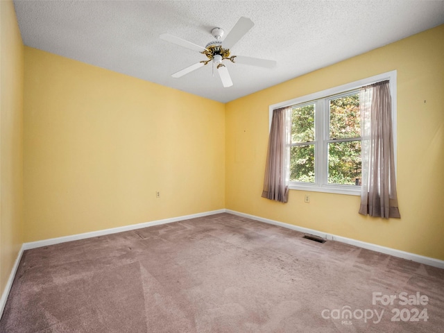 empty room featuring ceiling fan, carpet flooring, and a textured ceiling