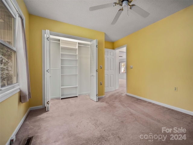 unfurnished bedroom featuring ceiling fan, light carpet, and multiple windows