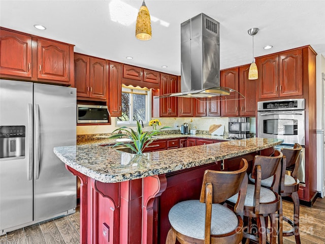 kitchen with light stone counters, appliances with stainless steel finishes, extractor fan, dark wood-type flooring, and decorative light fixtures