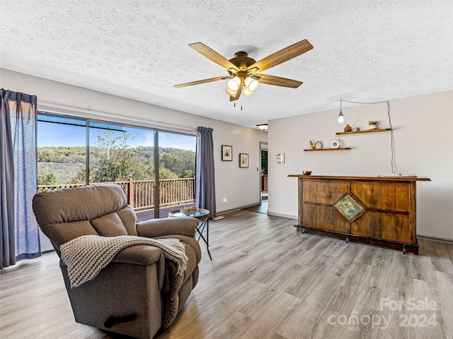 sitting room with a textured ceiling, light hardwood / wood-style floors, and ceiling fan