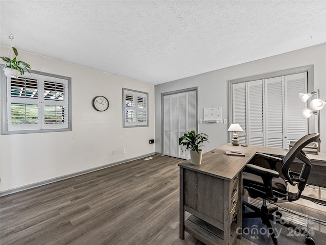 office featuring a textured ceiling, a healthy amount of sunlight, and dark wood-type flooring