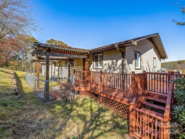 rear view of property featuring a wooden deck and a lawn