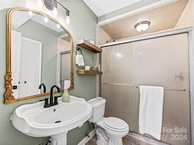 bathroom with toilet, walk in shower, sink, and tile patterned flooring