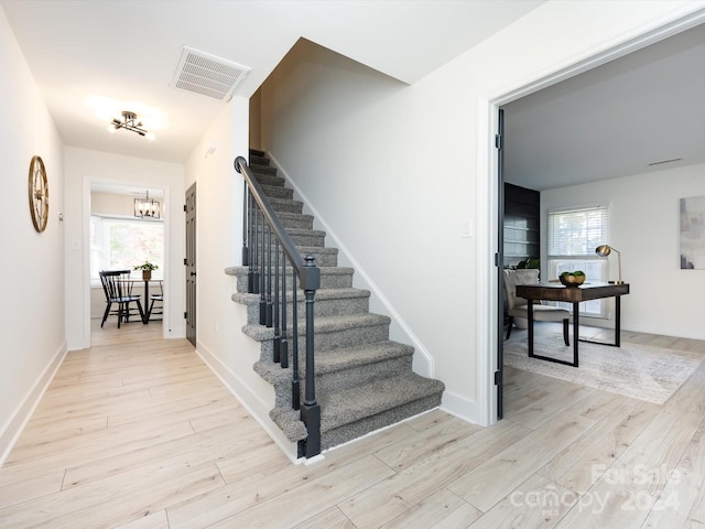 stairway with a notable chandelier and hardwood / wood-style floors