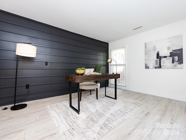 office area featuring light hardwood / wood-style floors and wooden walls