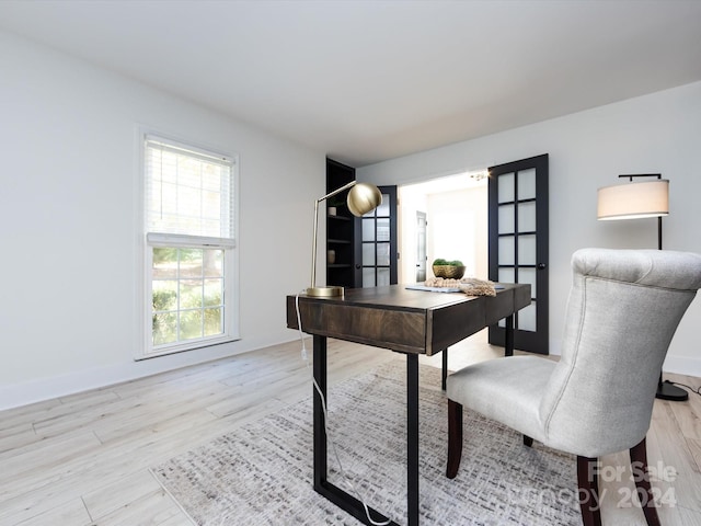 home office with french doors and light hardwood / wood-style floors