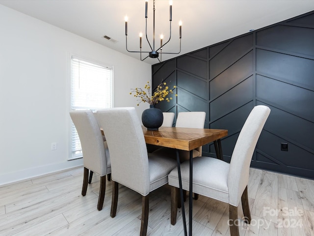 dining room with light hardwood / wood-style floors and a notable chandelier