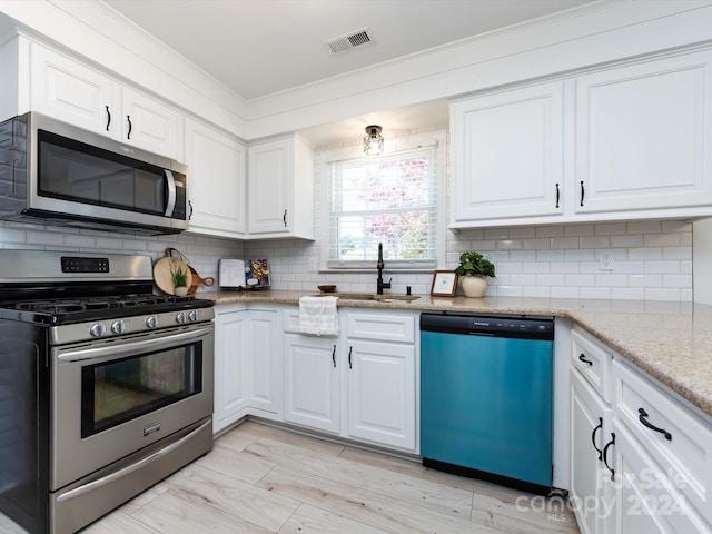 kitchen featuring white cabinetry, light stone countertops, stainless steel appliances, and sink