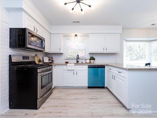 kitchen featuring tasteful backsplash, white cabinetry, light stone countertops, light hardwood / wood-style floors, and stainless steel appliances