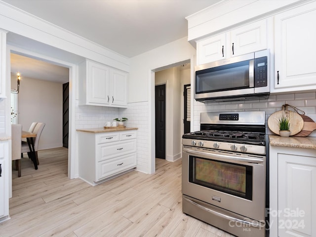 kitchen featuring stainless steel appliances, decorative backsplash, light wood-type flooring, and white cabinets