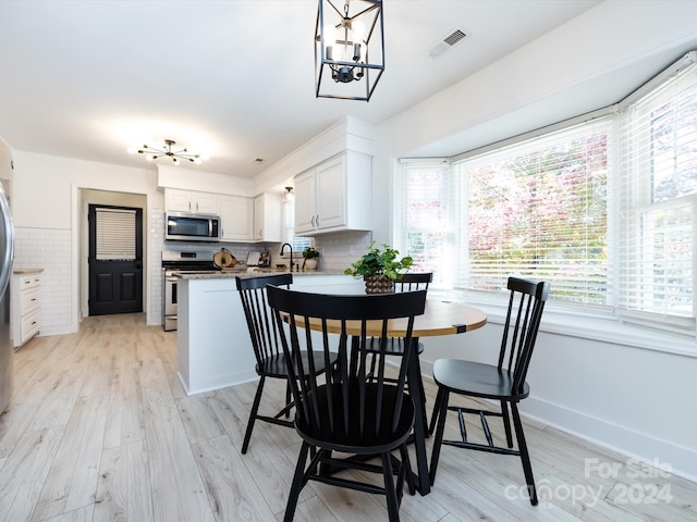 dining space featuring sink, a notable chandelier, and light hardwood / wood-style flooring