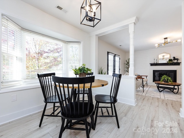 dining space featuring ornate columns, a notable chandelier, and light hardwood / wood-style flooring