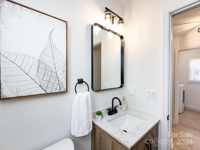 bathroom featuring toilet, hardwood / wood-style flooring, vanity, and washer / dryer