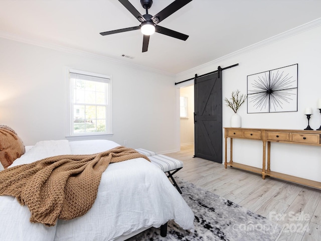 bedroom featuring ornamental molding, a barn door, light hardwood / wood-style floors, and ceiling fan