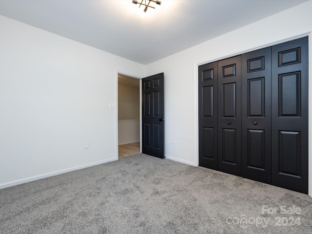 unfurnished bedroom with light colored carpet and a closet