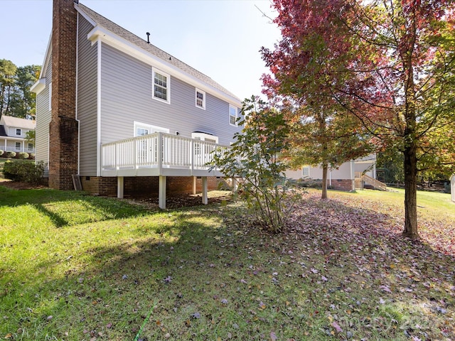 rear view of property with a wooden deck and a lawn