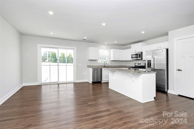 kitchen with white cabinetry, appliances with stainless steel finishes, a center island, and dark hardwood / wood-style floors