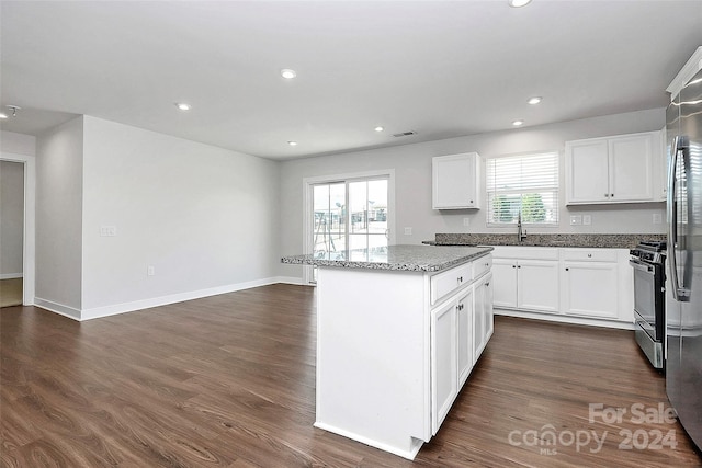 kitchen featuring a kitchen island, dark hardwood / wood-style flooring, white cabinetry, stainless steel stove, and light stone counters