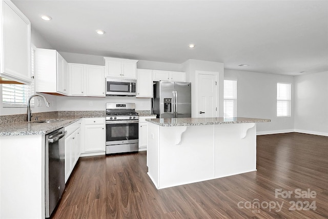 kitchen with sink, a kitchen island, dark hardwood / wood-style flooring, white cabinetry, and stainless steel appliances