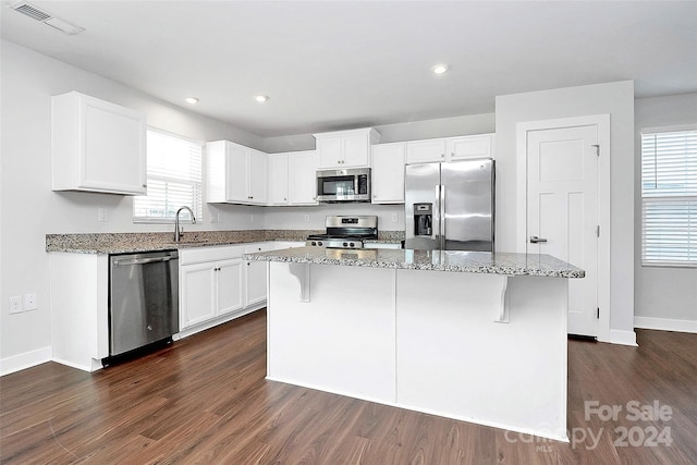 kitchen featuring a kitchen island, dark wood-type flooring, stainless steel appliances, and a healthy amount of sunlight