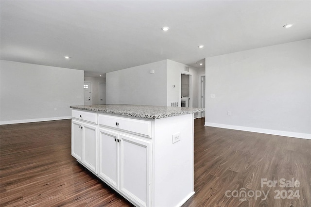 kitchen with white cabinetry, dark hardwood / wood-style floors, light stone counters, and a kitchen island