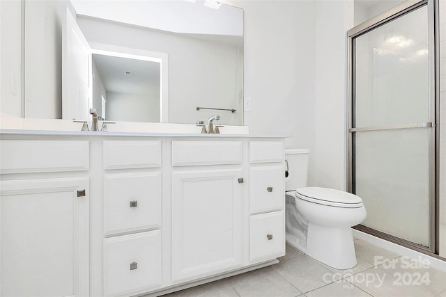 bathroom featuring vanity, toilet, tile patterned floors, and a shower with door