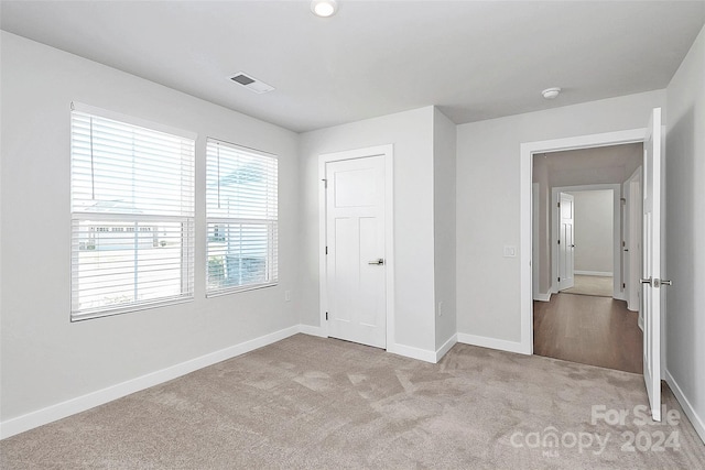 unfurnished bedroom featuring light colored carpet and a closet