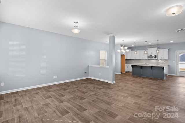 unfurnished living room with a notable chandelier and dark hardwood / wood-style flooring