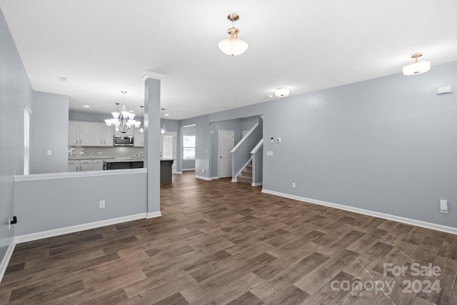 unfurnished living room with dark hardwood / wood-style floors and a chandelier